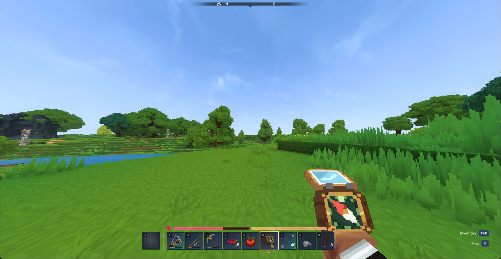 First-person view of a held pocket compass with a red needle, on a grassy Hytale meadow with a river and trees behind.